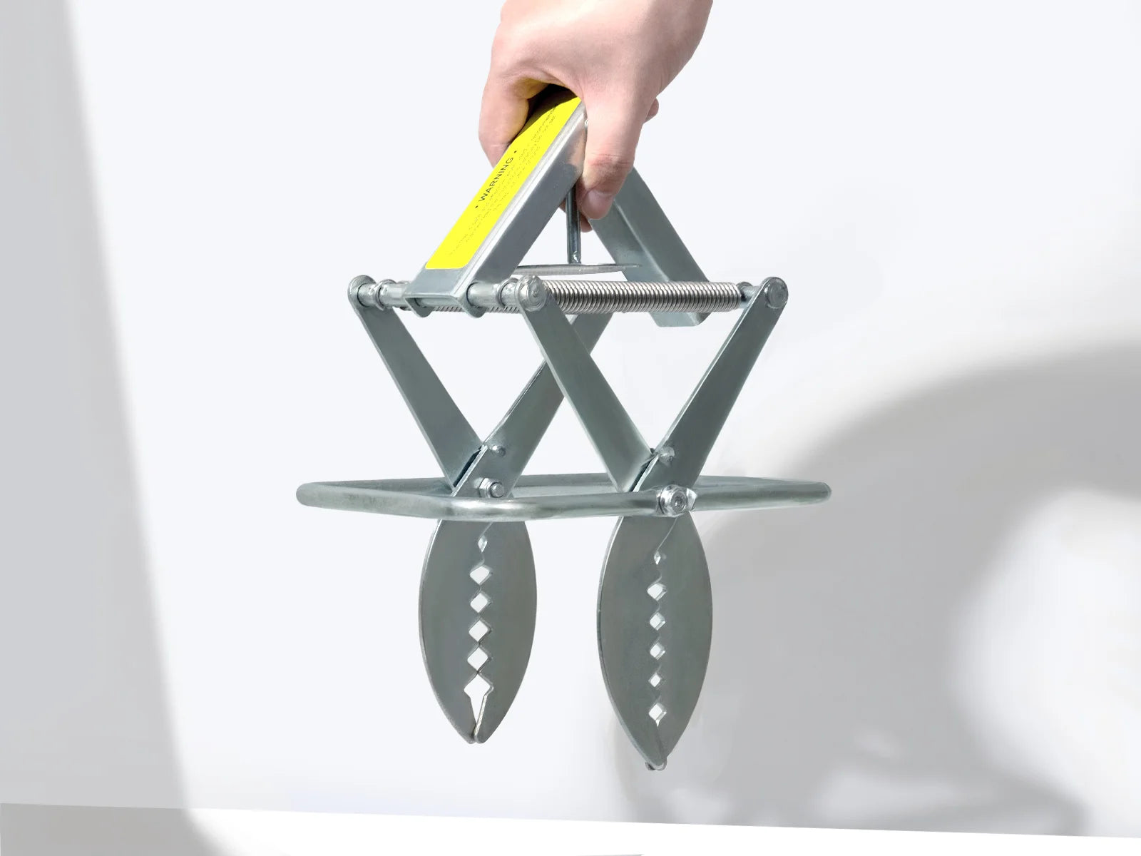 Metal mole trap for yard held by a hand on a white background

